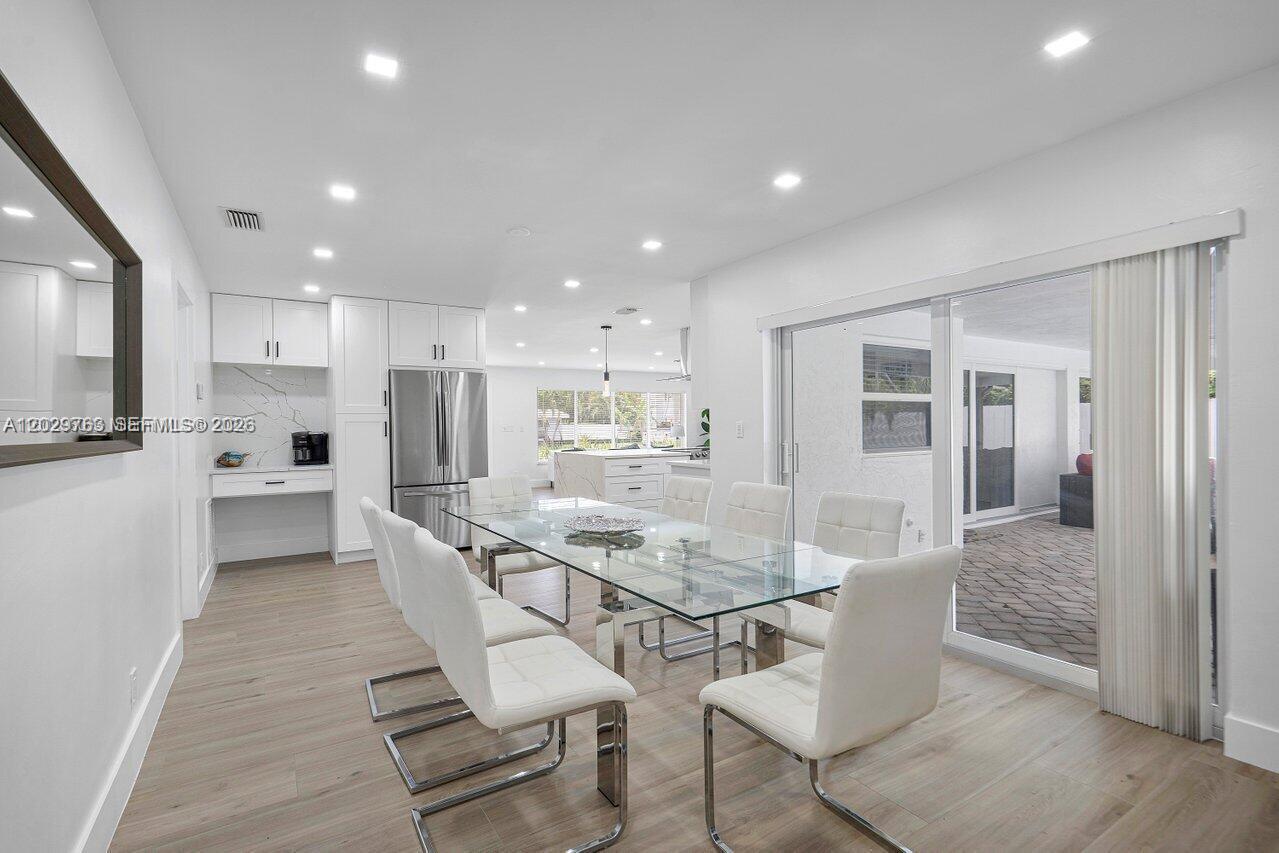 A dining room with a glass table, white chairs, and an adjacent modern kitchen — 6991 NE 7th Ave # 0, Boca Raton FL 33487, BOCA RATON, FL