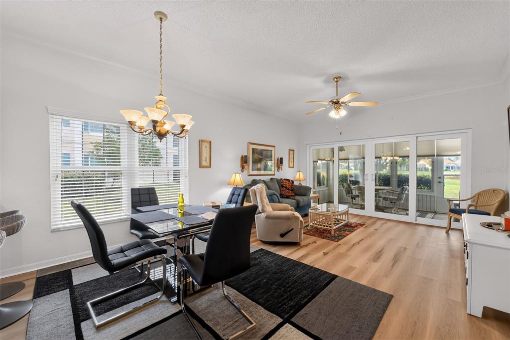 A dining area and living room with light wood floors, a ceiling fan, and sliding doors — 4706 SAND TRAP STREET CIRCLE E UNIT 101, BRADENTON, FL