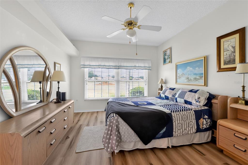 A bedroom features a bed with nautical bedding, a wooden dresser with a mirror, and a ceiling fan — 4706 SAND TRAP STREET CIRCLE E UNIT 101, BRADENTON, FL