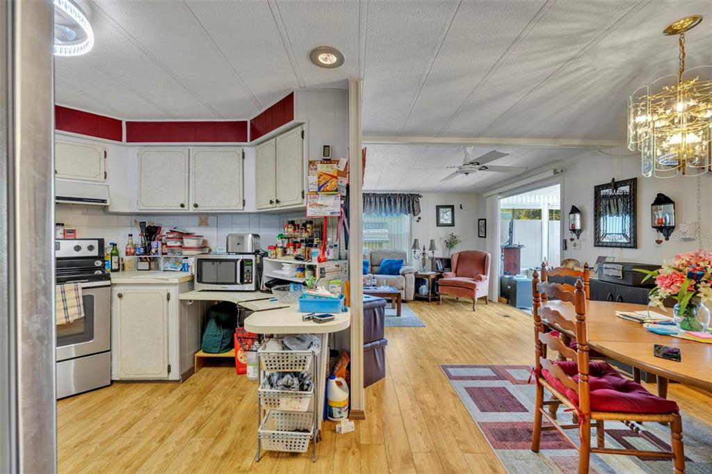 A kitchen with white cabinets and a dining area featuring wood flooring and a chandelier — 223 PARADISE S, LEESBURG, FL
