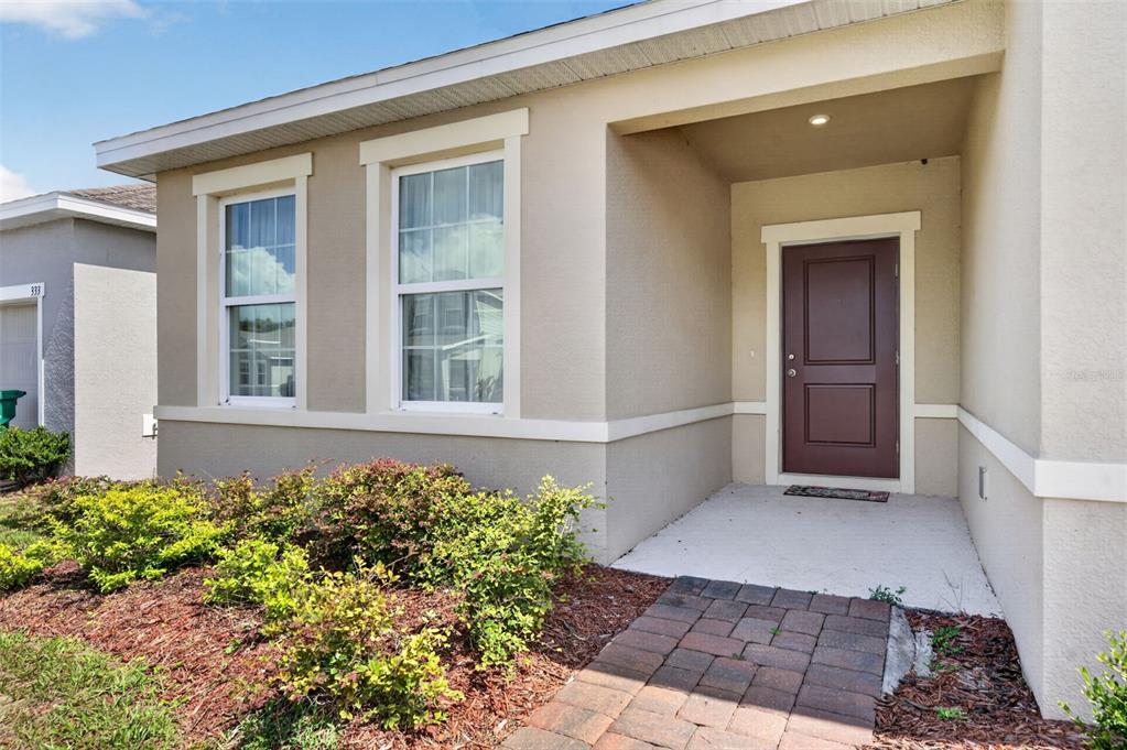 The exterior of a house features a brown front door, two windows, and a walkway — 341 WINTER BLISS LANE, MOUNT DORA, FL