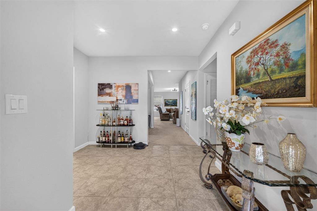 An open-concept living room and kitchen featuring light wood floors, neutral furniture, and cabinetry — 341 WINTER BLISS LANE, MOUNT DORA, FL