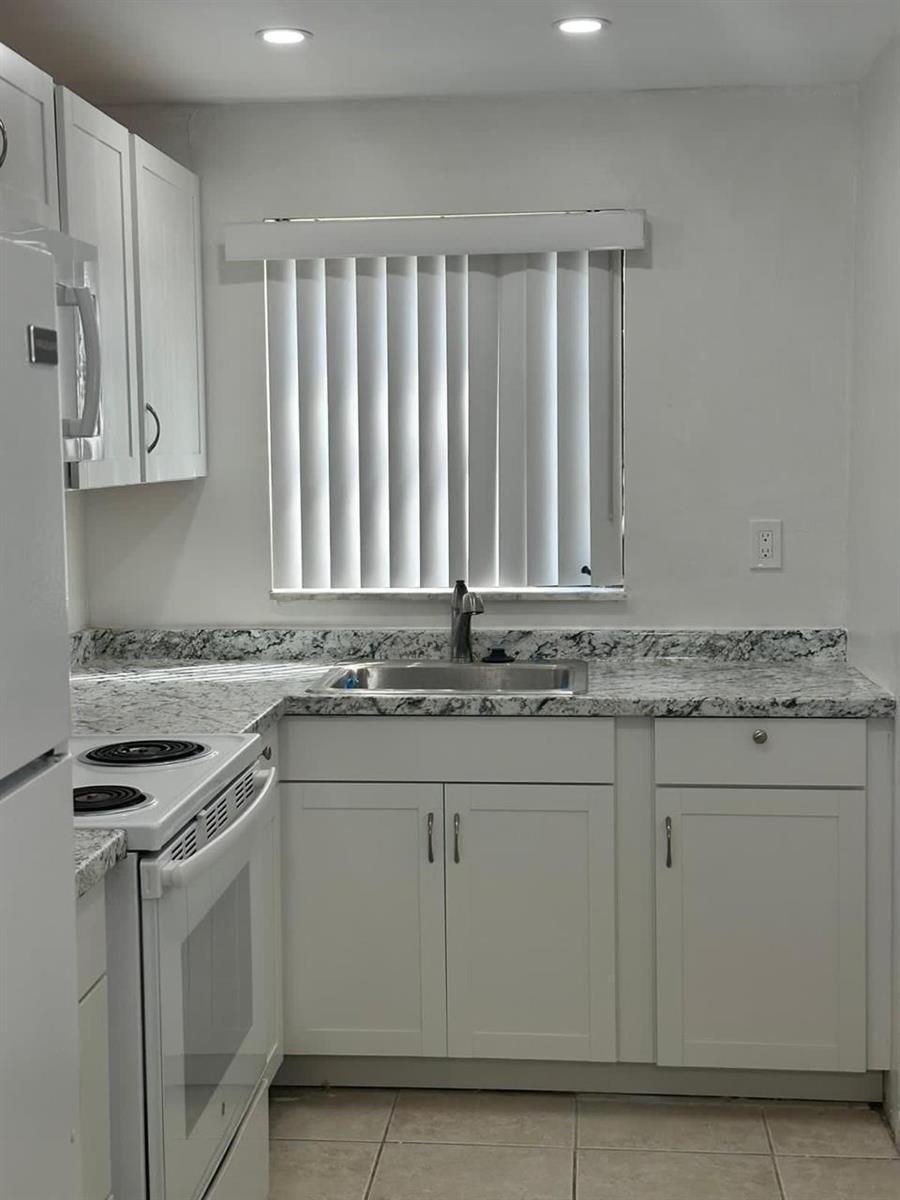 A kitchen features white cabinets, granite countertops, a stainless steel sink, and a window — 50 SE 12th Street # 145, Boca Raton FL 33432, BOCA RATON, FL