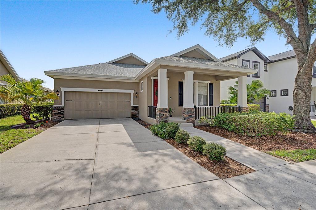 A single-story house features a tan exterior, a two-car garage, and a covered front porch — 8152 LAGERFELD DRIVE, LAND O LAKES, FL