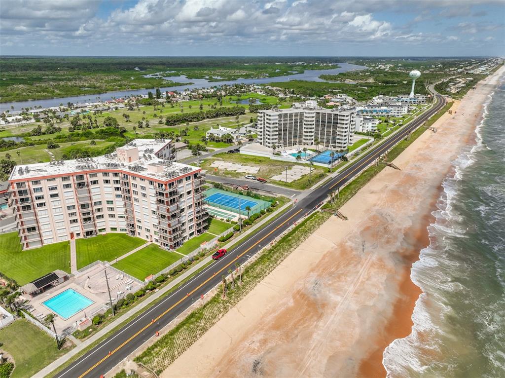 An aerial view shows two beachfront apartment buildings, a road, and a sandy coastline — 3600 S OCEAN SHORE BOULEVARD UNIT 812, FLAGLER BEACH, FL