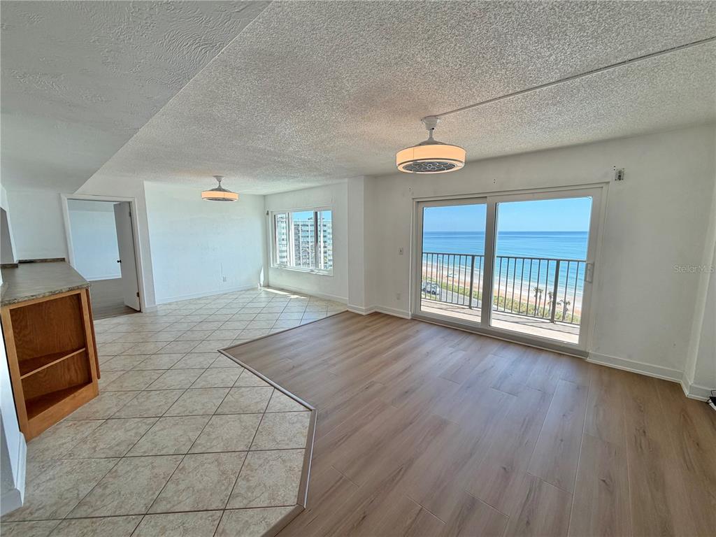A living area with wood-look flooring and tile features a sliding door overlooking the ocean — 3600 S OCEAN SHORE BOULEVARD UNIT 812, FLAGLER BEACH, FL