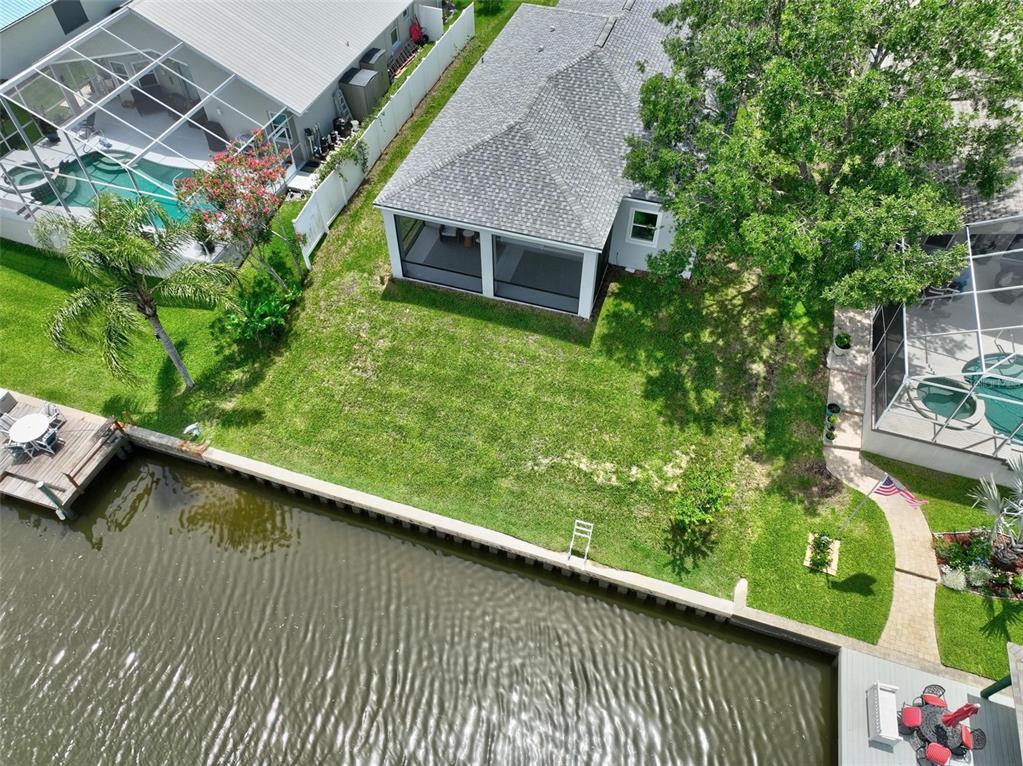 An aerial view shows a waterfront backyard with a lawn, a seawall, and screened lanais — 56 COLUMBIA LANE, PALM COAST, FL