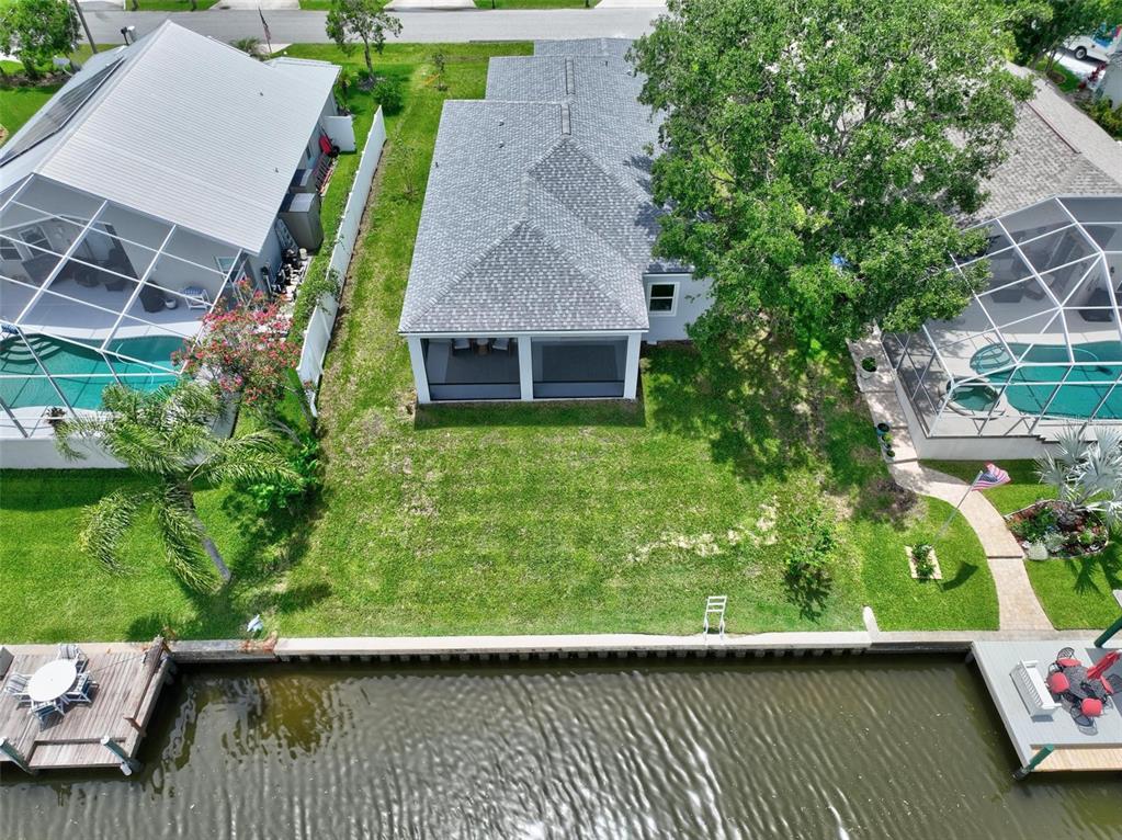An aerial view shows a house with a screened porch, backyard, and private canal dock — 56 COLUMBIA LANE, PALM COAST, FL