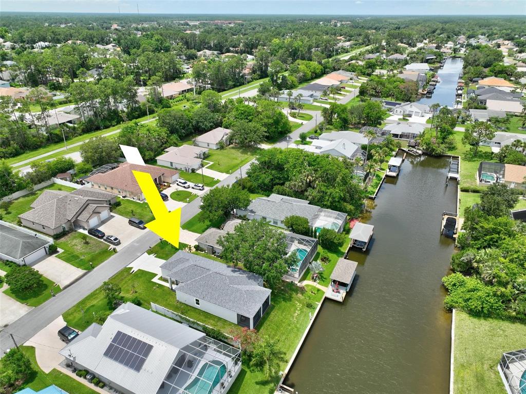 An aerial view shows a residential house with a gray roof and a canal-side backyard — 56 COLUMBIA LANE, PALM COAST, FL