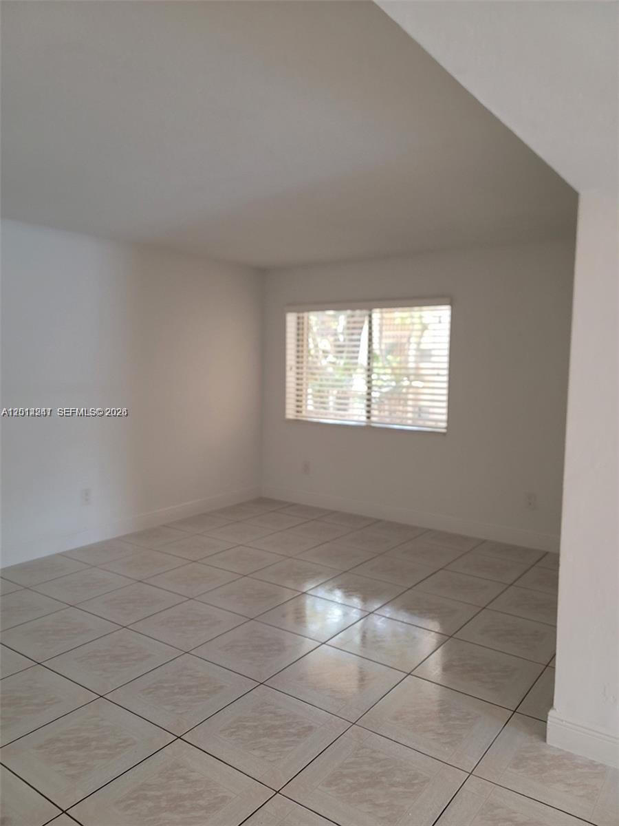 An empty room features white walls, a single window with blinds, and tiled flooring — 8401 SW 107 AVE # 260E, Miami FL 33173, MIAMI, FL