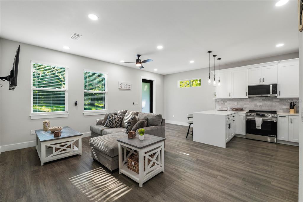 An open-concept living room and kitchen with gray wood floors, white cabinets, and gray furniture — 192-194 S LEMON AVENUE, BROOKSVILLE, FL