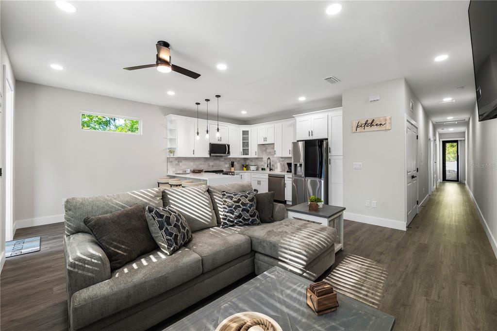 A modern open-concept living room and kitchen feature gray flooring, white cabinetry, and a sectional sofa — 192-194 S LEMON AVENUE, BROOKSVILLE, FL