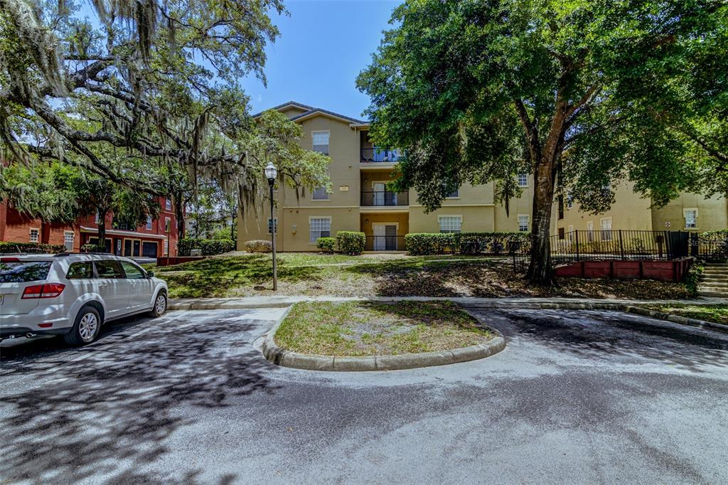 A tan, multi-story building with a central entrance, stairs, and a prominent tower feature — 114 VISTA VERDI CIRCLE UNIT 116, LAKE MARY, FL