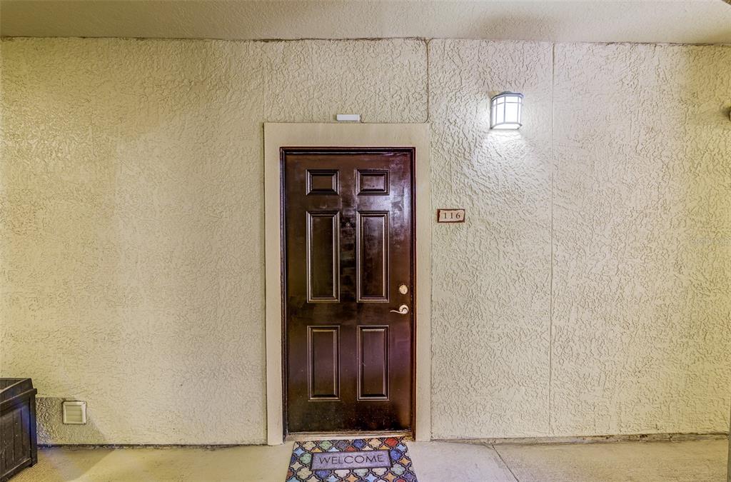 A covered outdoor walkway leads to a dark brown door and an exit door — 114 VISTA VERDI CIRCLE UNIT 116, LAKE MARY, FL