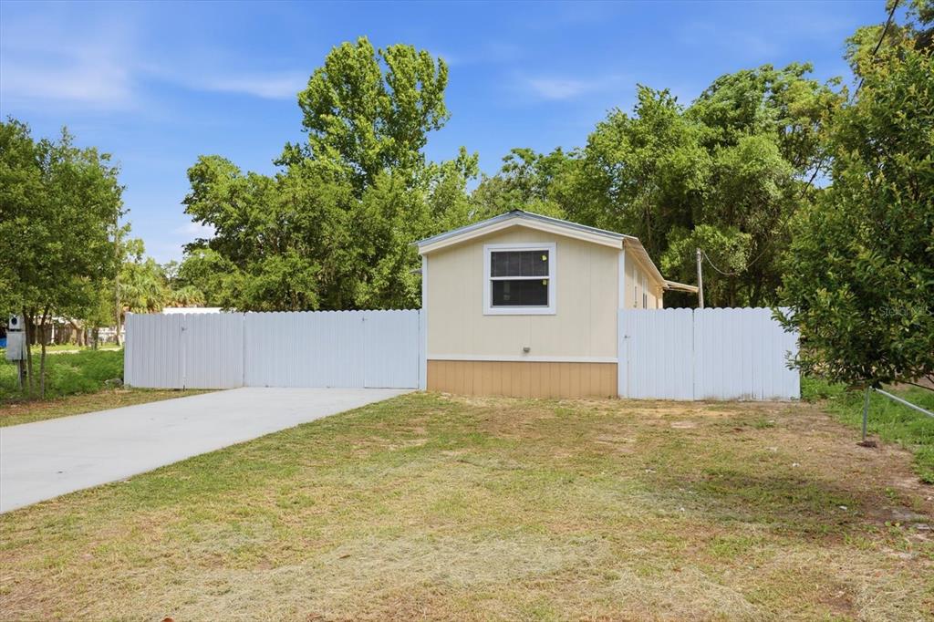 A single-story mobile home with tan siding sits behind a white vinyl privacy fence — 6403 W TANGERINE LANE, CRYSTAL RIVER, FL