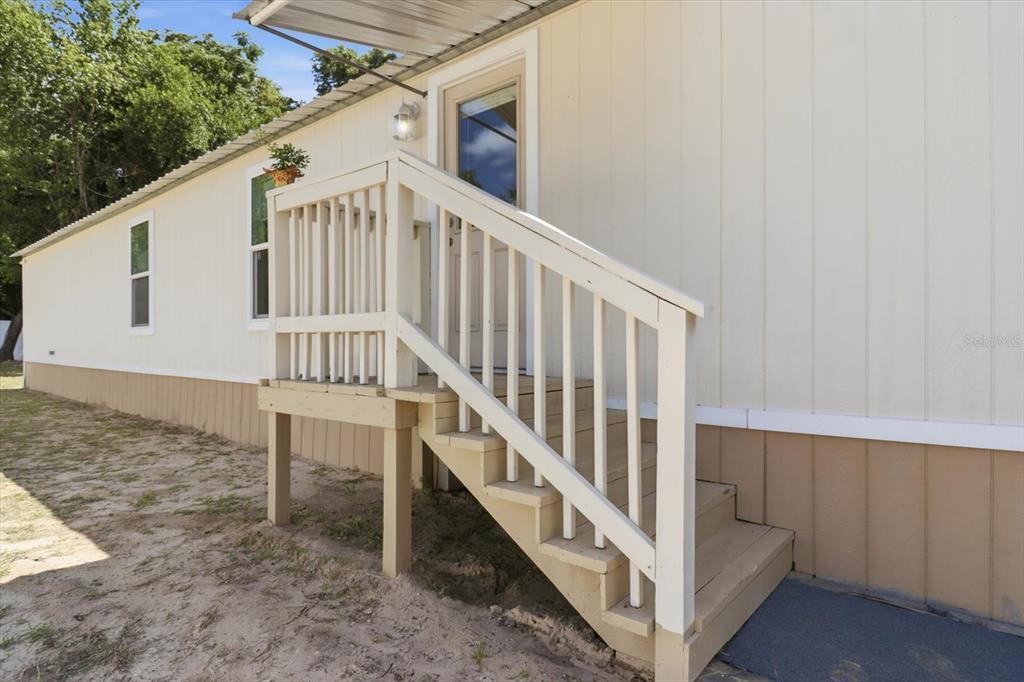 A mobile home exterior features a wooden staircase leading to a side entrance door — 6403 W TANGERINE LANE, CRYSTAL RIVER, FL