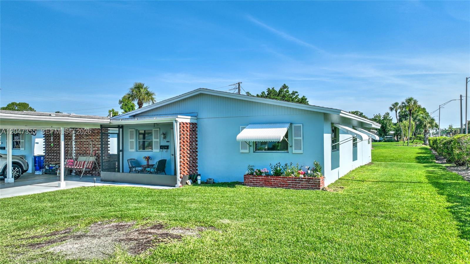 A light blue single-story house features a screened-in porch, brick accents, and a brick planter — 2201 Croton Ct., Lehigh Acres FL 33936, LEHIGH ACRES, FL