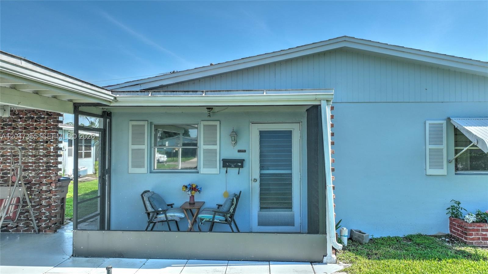 A light blue house features a screened-in front porch with a small table and chairs — 2201 Croton Ct., Lehigh Acres FL 33936, LEHIGH ACRES, FL