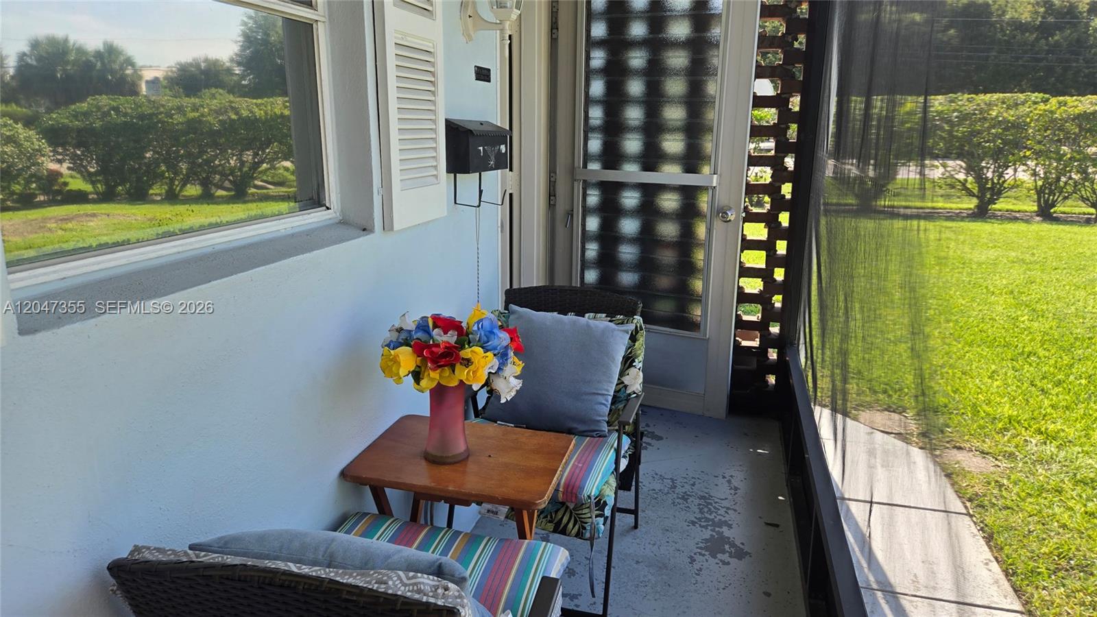 A small, screened-in porch features a wooden side table, a chair, and a flower vase — 2201 Croton Ct., Lehigh Acres FL 33936, LEHIGH ACRES, FL