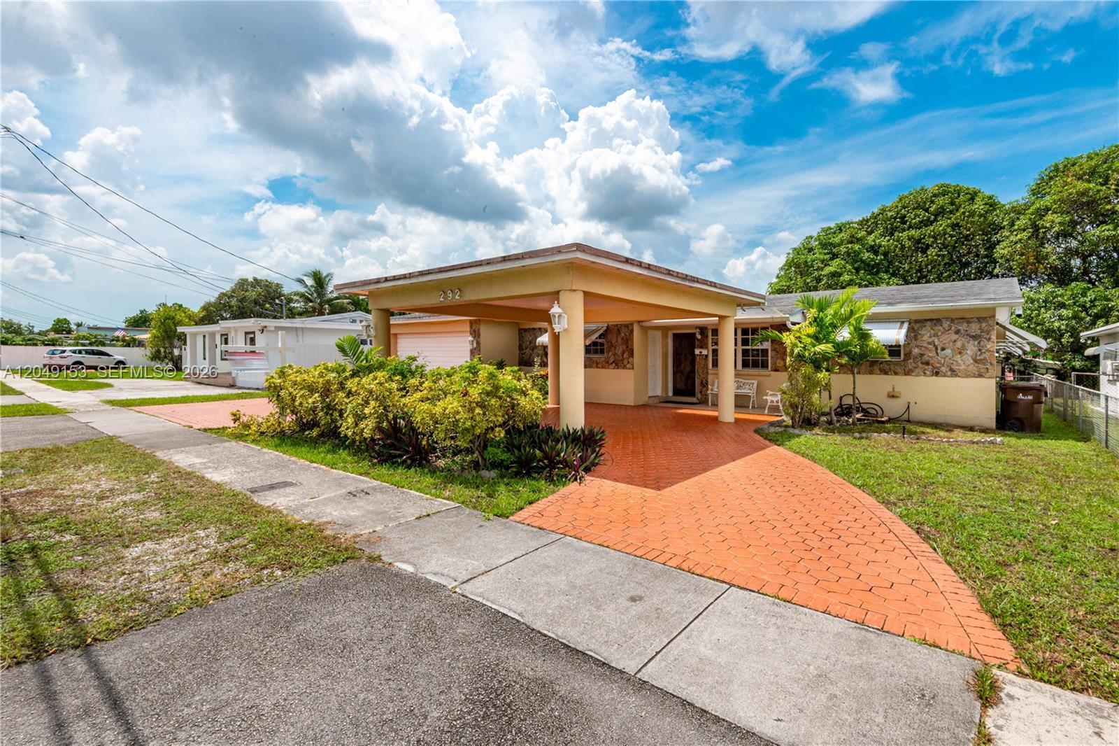 A single-story house features a covered carport, stone facade, and a paved orange driveway — 292 W 39th Pl, Hialeah FL 33012, HIALEAH, FL