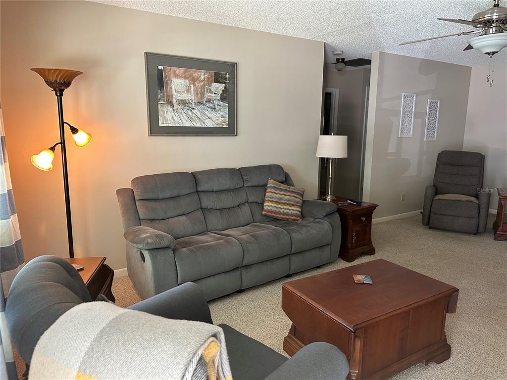 A living room features a gray sofa, a wooden coffee table, and a recliner chair — 8680 SW 94TH LANE UNIT G, OCALA, FL