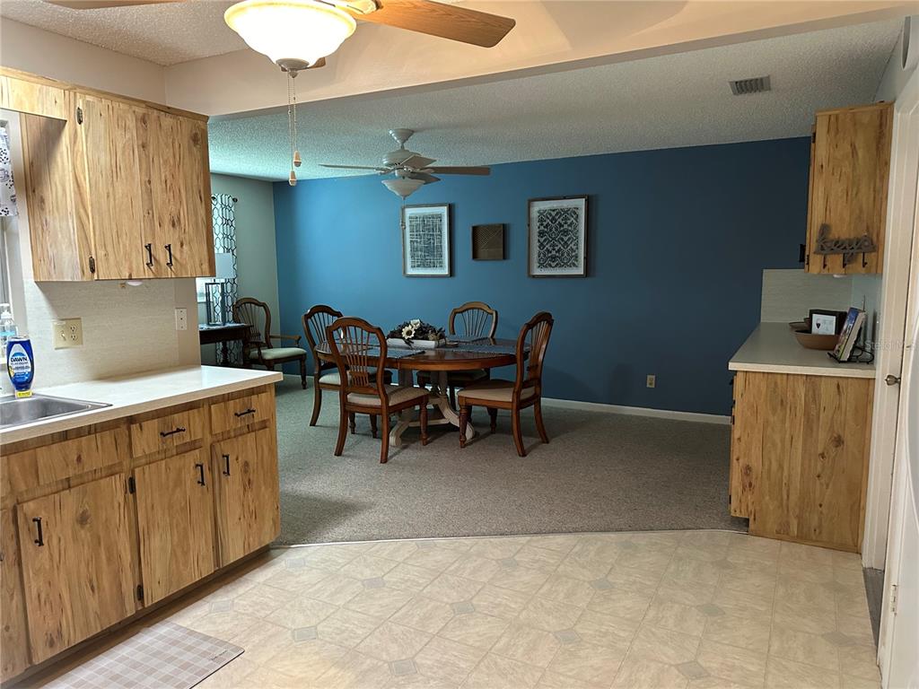 A kitchen with wood cabinets and a dining area featuring a blue accent wall — 8680 SW 94TH LANE UNIT G, OCALA, FL