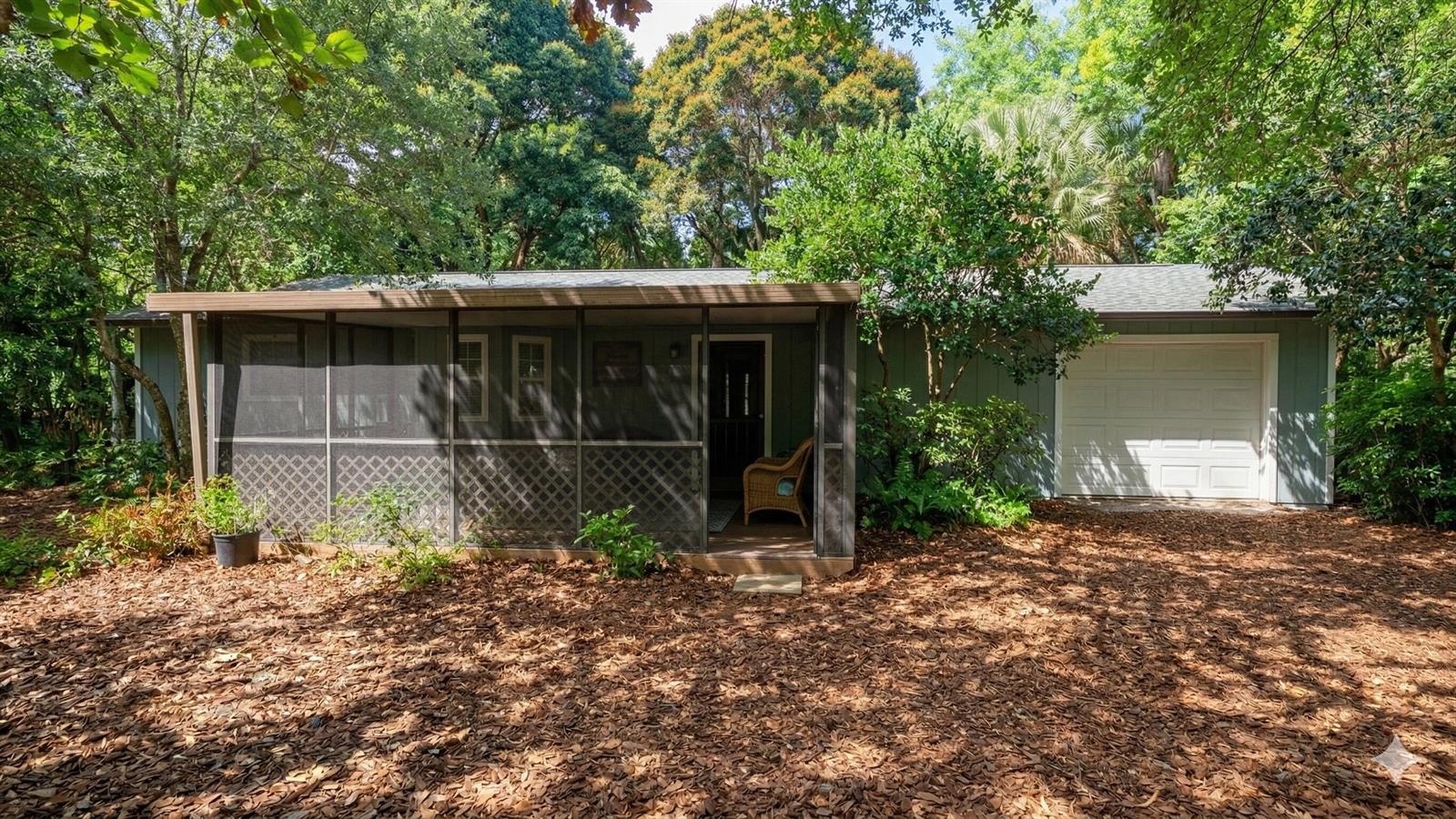 A single-story house with a screened-in porch and an attached garage sits in a wooded area — 5679 Sims Road, Delray Beach FL 33484, DELRAY BEACH, FL