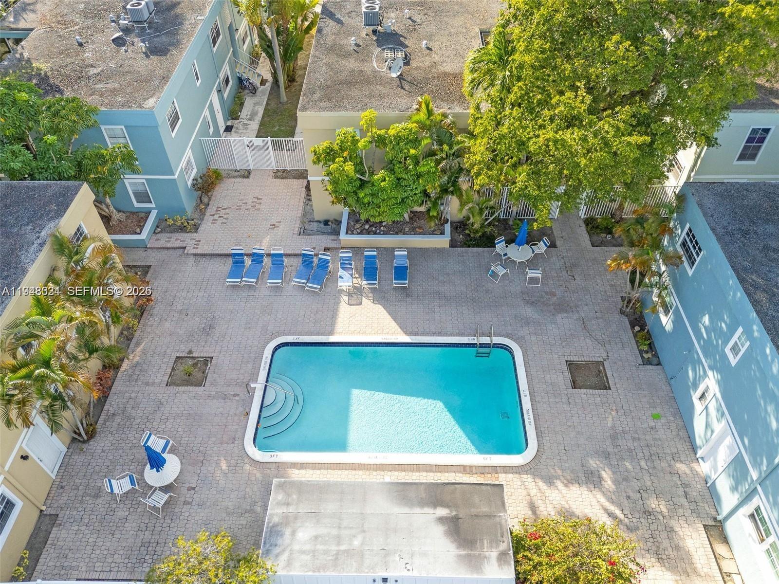An aerial view shows a rectangular swimming pool surrounded by a paved patio and lounge chairs — 320 SE 10th Ave # D, Pompano Beach FL 33060, POMPANO BEACH, FL