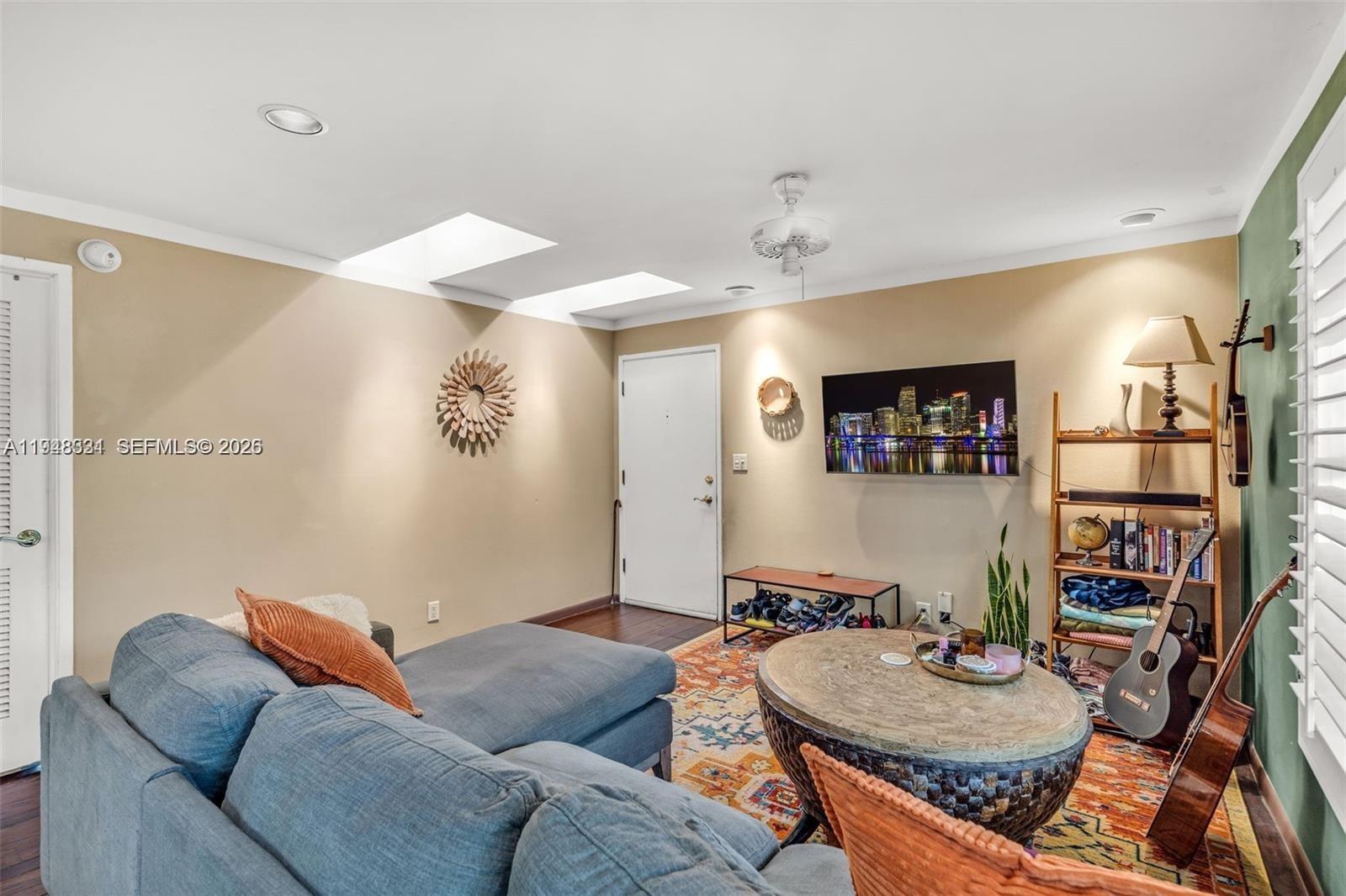 A living room features a blue sectional sofa, a round coffee table, and a wall-mounted television — 320 SE 10th Ave # D, Pompano Beach FL 33060, POMPANO BEACH, FL