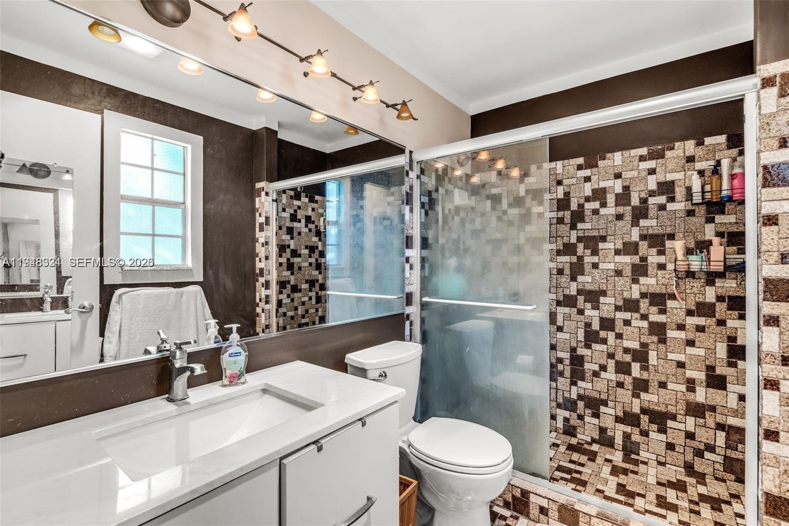 A bathroom features a white vanity, a large mirror, and a tiled walk-in shower — 320 SE 10th Ave # D, Pompano Beach FL 33060, POMPANO BEACH, FL