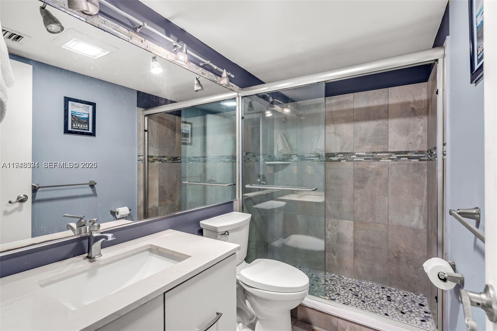 A bathroom features a white vanity, a toilet, and a glass-enclosed shower with tiled walls — 320 SE 10th Ave # D, Pompano Beach FL 33060, POMPANO BEACH, FL