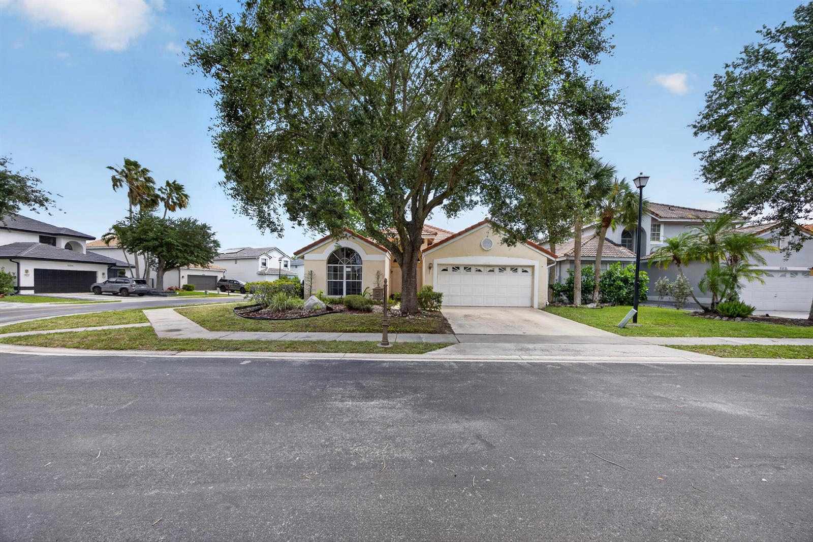 A single-story house with a two-car garage and a large tree in the front yard — 10870 Old Bridgeport Lane, Boca Raton FL 33498, BOCA RATON, FL