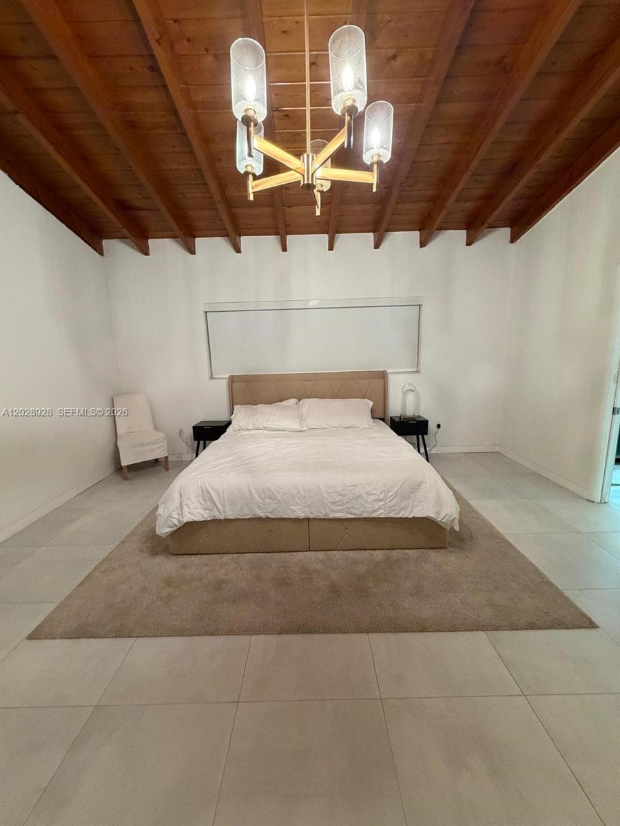 A bedroom features a tufted bed, a large area rug, and a wood-beamed ceiling — 3600 SW 26th St, Miami FL 33133, MIAMI, FL