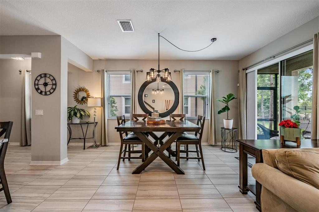A dining room features a wooden table, a circular mirror, and tile flooring — 29947 SOUTHWELL LANE, WESLEY CHAPEL, FL