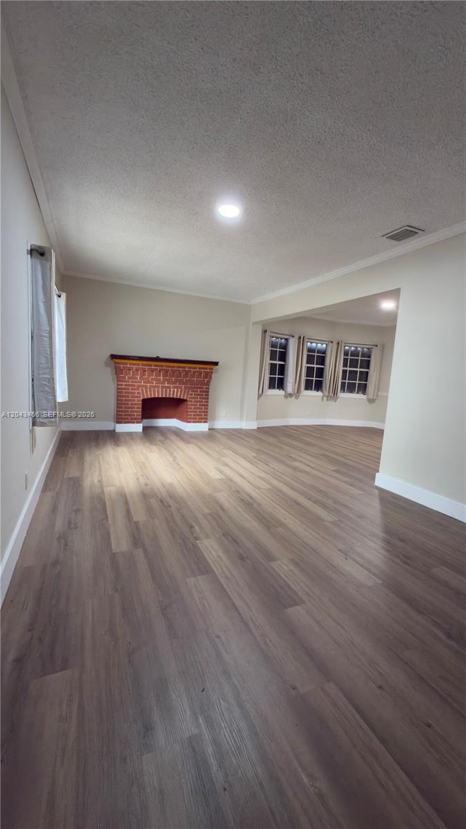 A living room features light wood-look flooring, beige walls, and a red brick fireplace — 103 NW 35th St, Miami FL 33127, MIAMI, FL
