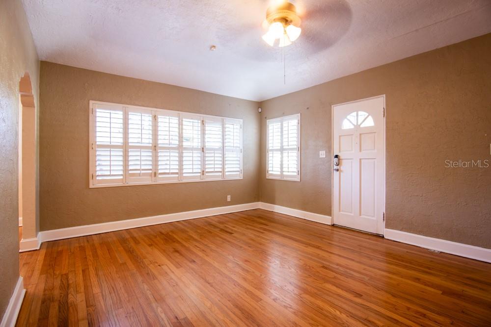 An empty room with tan walls, hardwood floors, white plantation shutters, and a ceiling fan — 1840 BAYLARIAN BOULEVARD, ORLANDO, FL