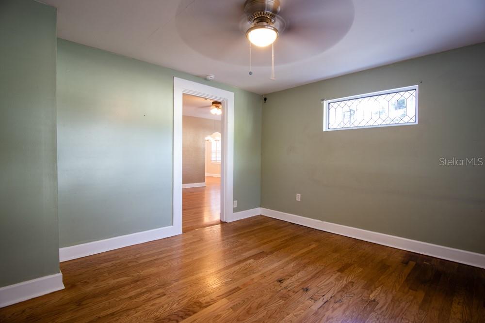 An empty room with sage green walls, hardwood floors, a ceiling fan, and a transom window — 1840 BAYLARIAN BOULEVARD, ORLANDO, FL