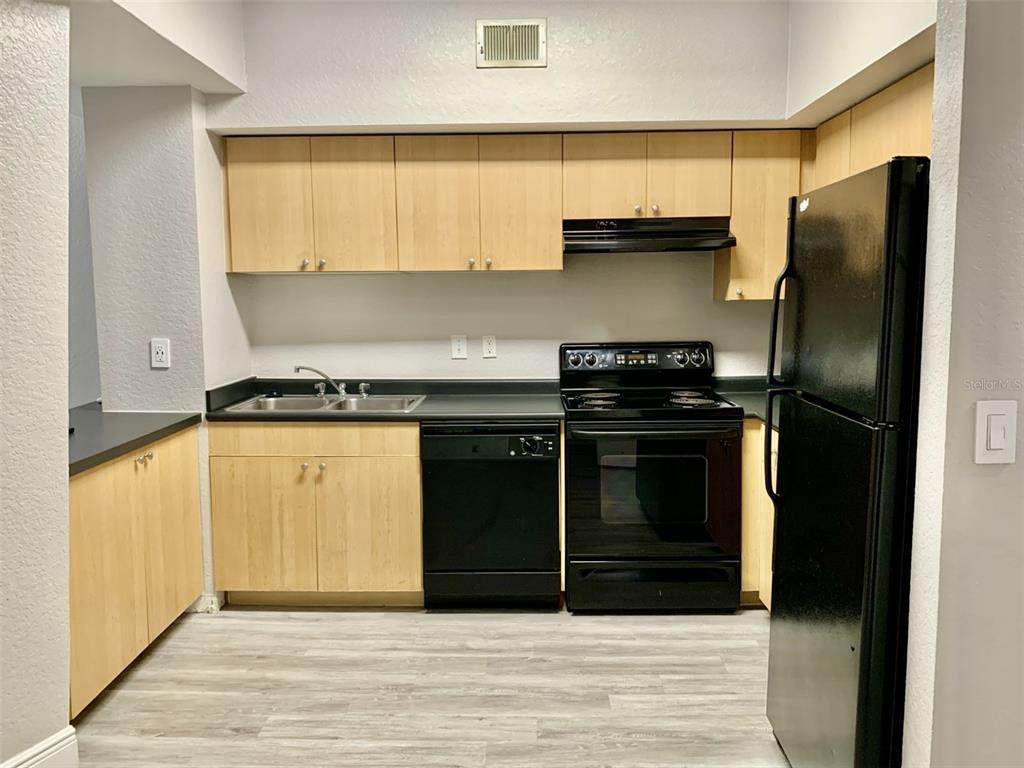 A kitchen features light wood cabinets, black appliances, a double sink, and grey wood-look flooring — 520 S ARMENIA AVENUE UNIT 1235, TAMPA, FL