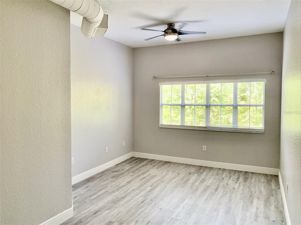 An empty room with light gray walls, wood-look flooring, a ceiling fan, and a window — 520 S ARMENIA AVENUE UNIT 1235, TAMPA, FL