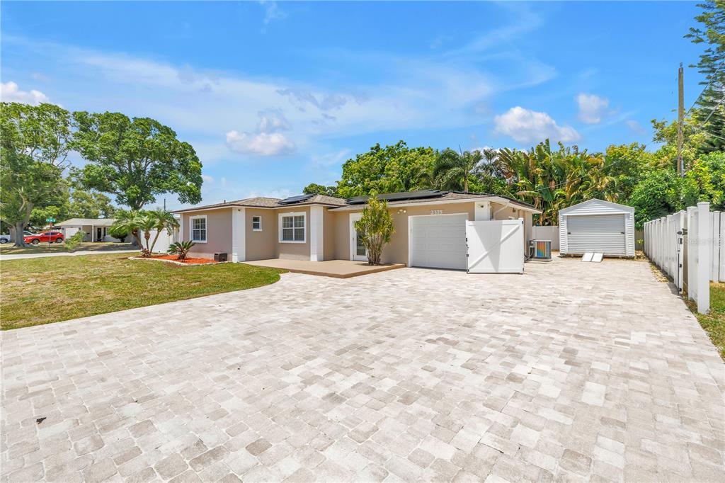 A single-story house with a paved driveway, a white garage door, and a detached shed — 2375 37TH STREET N, ST PETERSBURG, FL