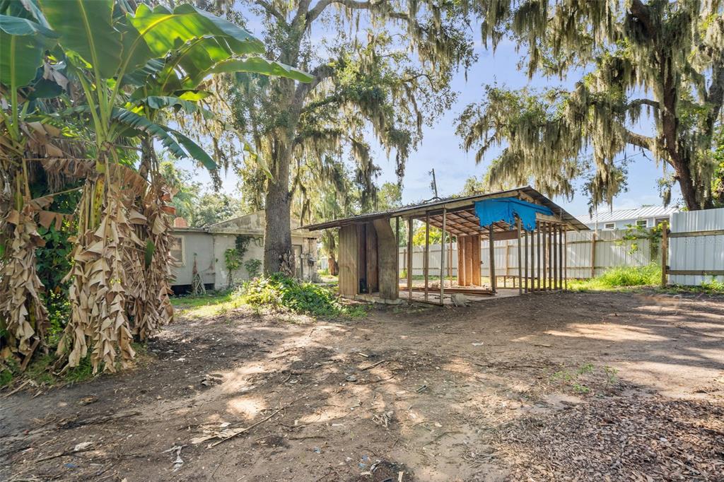 An outdoor view shows a small, weathered house next to an open-sided wooden shed structure — 3415 41ST STREET E, PALMETTO, FL