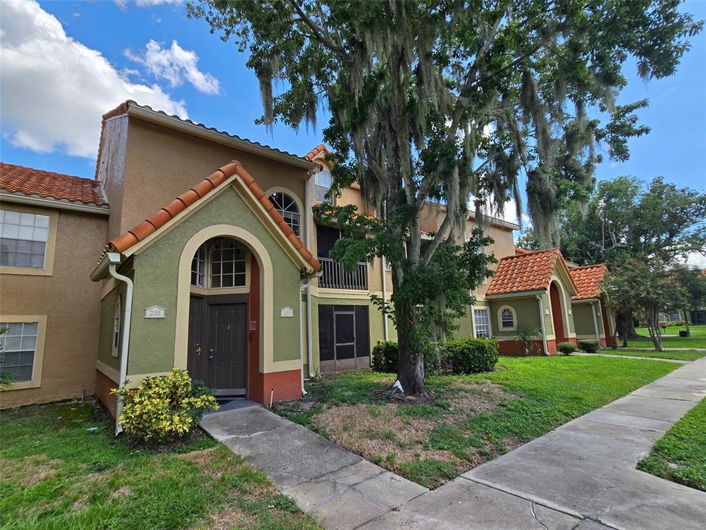 A multi-story apartment building with stucco walls, arched entryways, and a tile roof — 409 FOUNTAINHEAD CIRCLE, KISSIMMEE, FL