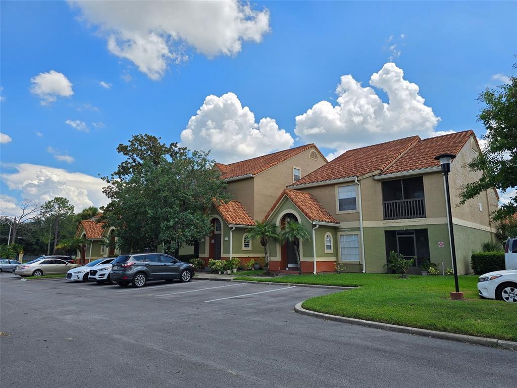 A multi-story apartment building with a tiled roof and parking lot in front — 409 FOUNTAINHEAD CIRCLE, KISSIMMEE, FL
