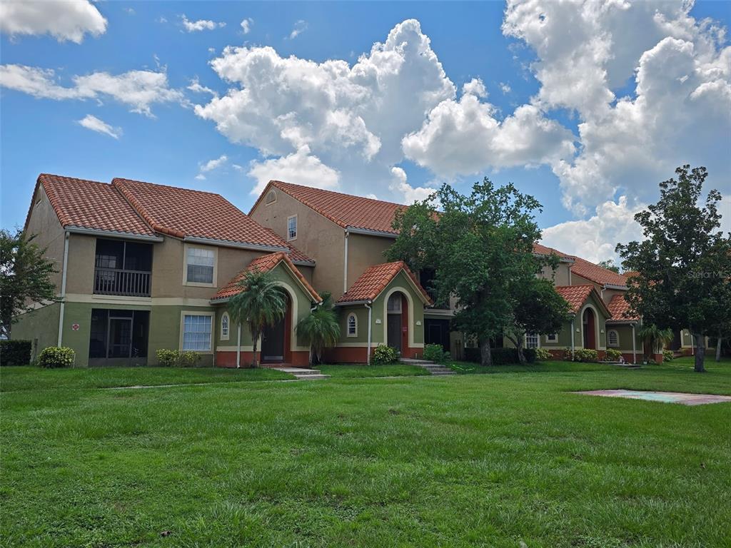 A multi-story apartment building with a stucco exterior and a red tile roof — 409 FOUNTAINHEAD CIRCLE, KISSIMMEE, FL