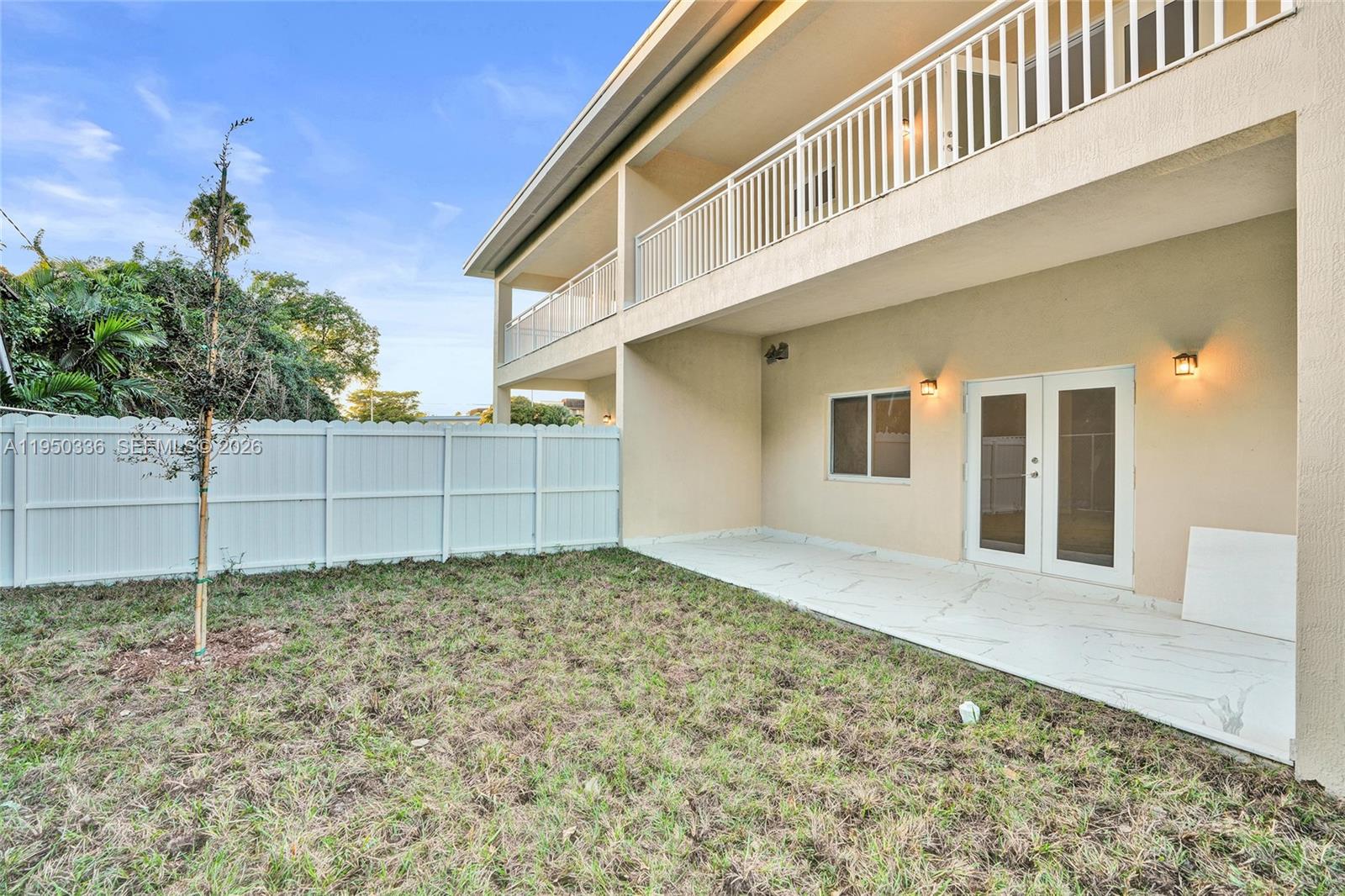 A backyard features a white fence, a marble-tiled patio, and a two-story house exterior — 250 NE 119th Terrace, Miami FL 33161, MIAMI, FL