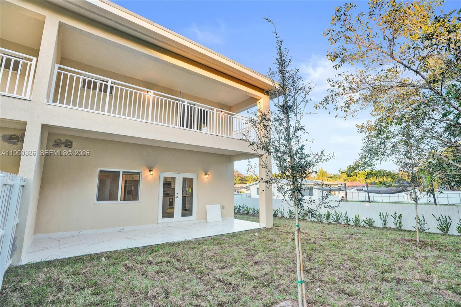 A two-story house exterior features a white-railed balcony, a tiled patio, and a grassy yard — 250 NE 119th Terrace, Miami FL 33161, MIAMI, FL