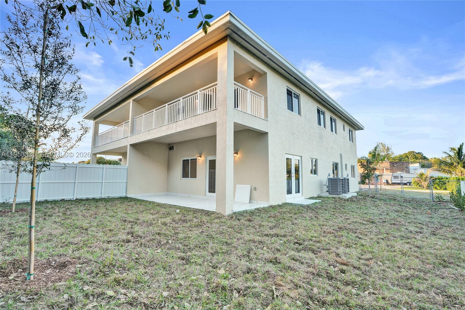 The exterior of a two-story house features a covered patio, balcony, and white fencing — 250 NE 119th Terrace, Miami FL 33161, MIAMI, FL