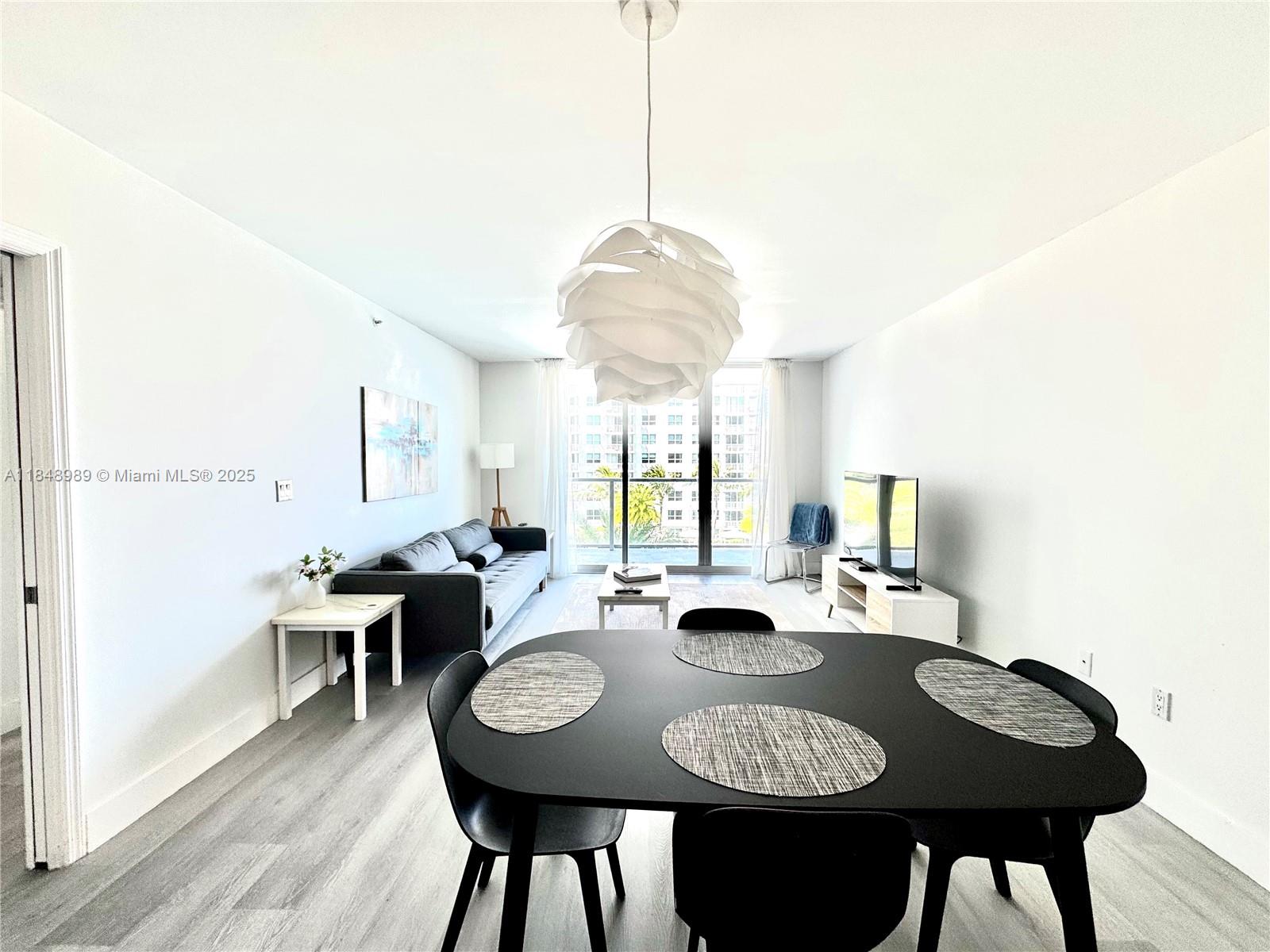 A dining area with a black table leads into a living room with a balcony — 1155 Brickell Bay Dr # 906, Miami FL 33131, MIAMI, FL
