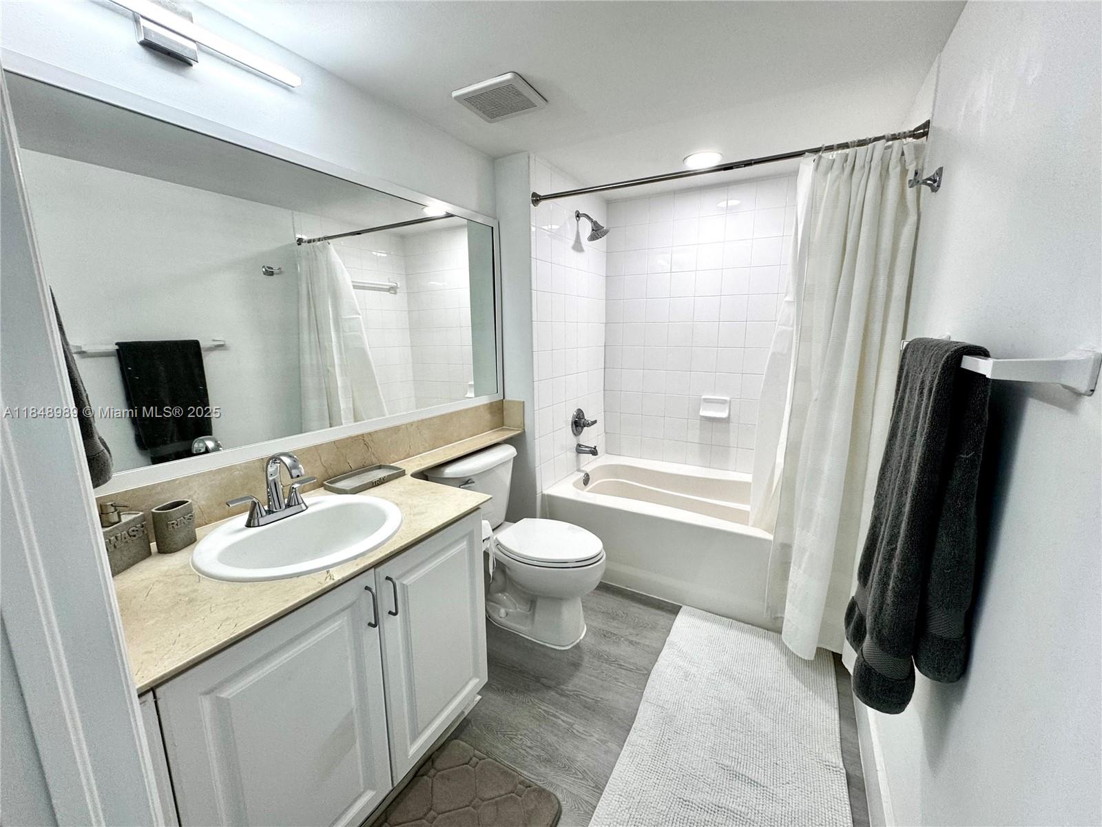A bathroom features a white vanity, a beige countertop, a toilet, and a tiled tub — 1155 Brickell Bay Dr # 906, Miami FL 33131, MIAMI, FL