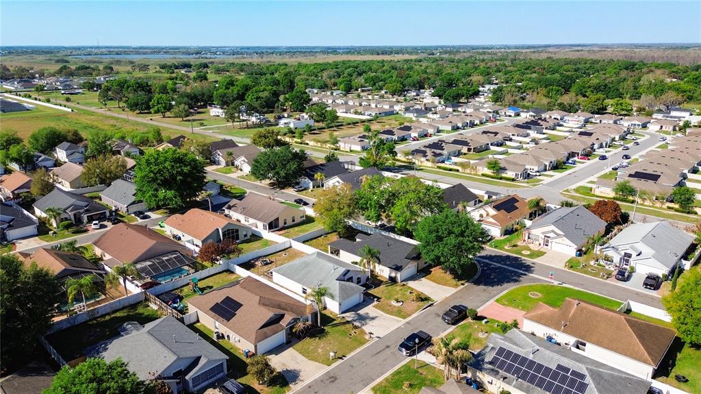 An aerial view shows a suburban neighborhood with many houses featuring solar panels on roofs — 233 VERBENA STREET, DAVENPORT, FL